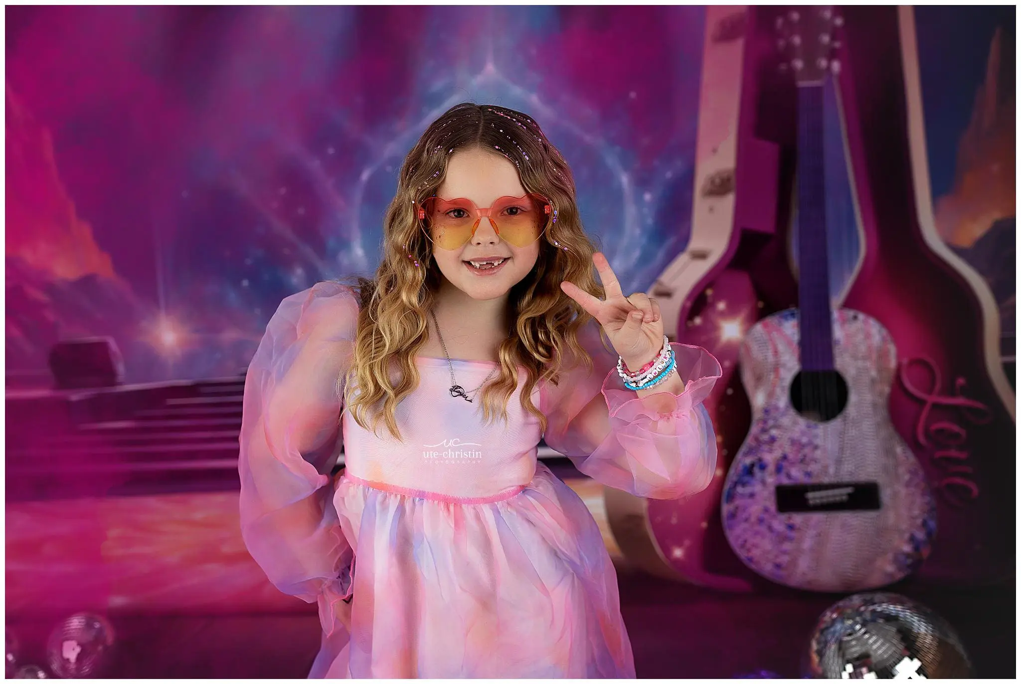 A smiling girl with wavy hair wearing a pastel dress and orange-tinted glasses flashes a peace sign, channeling Taylor Swift vibes. She stands before a colorful, dreamy background filled with guitars and disco balls.