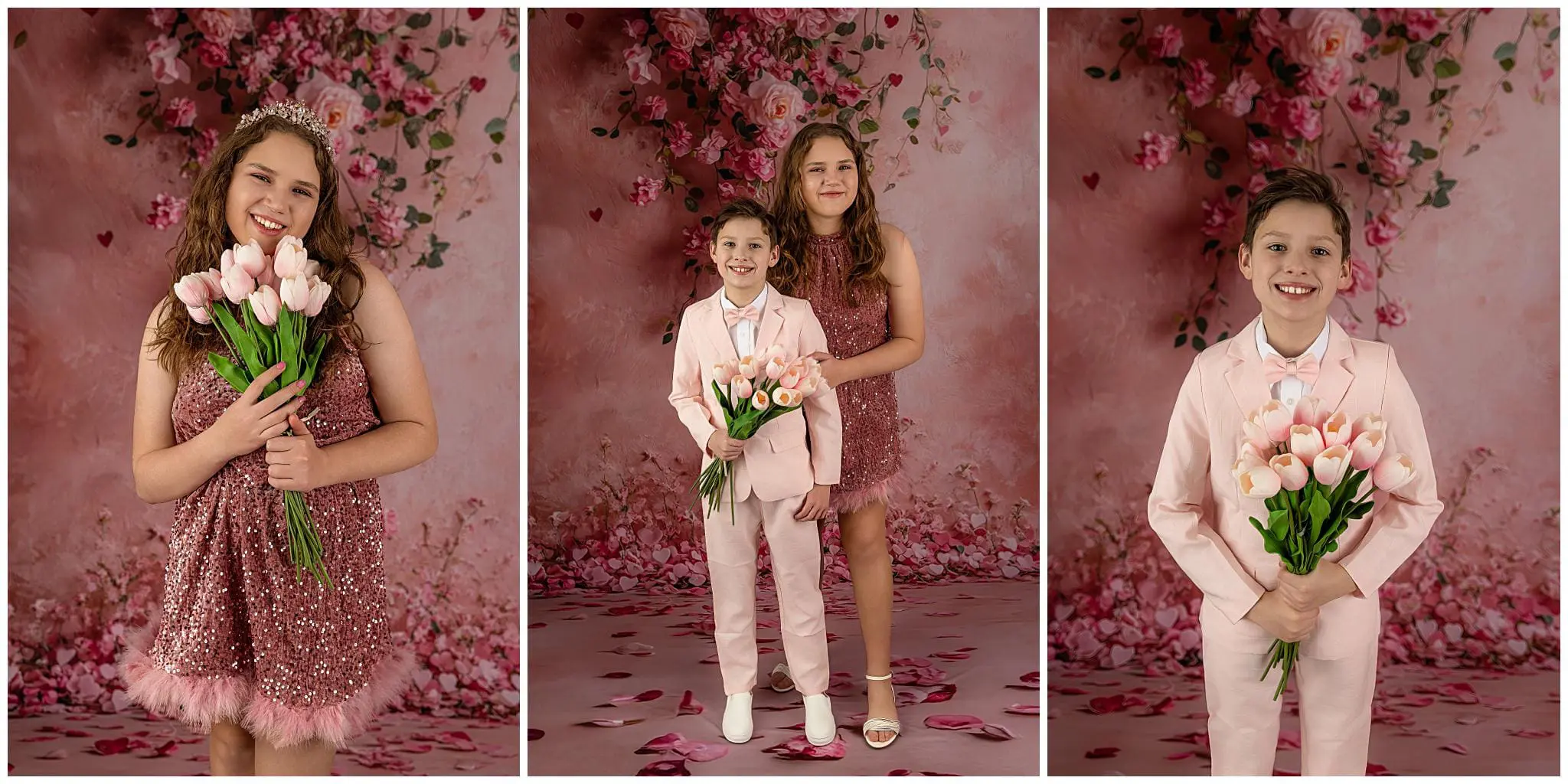 Three children posing against a pink floral backdrop. Left: girl in sparkly pink dress holding tulips. Center: boy in pink suit and girl in pink dress, both smiling. Right: boy in pink suit holding tulips. Pink petals on the floor.