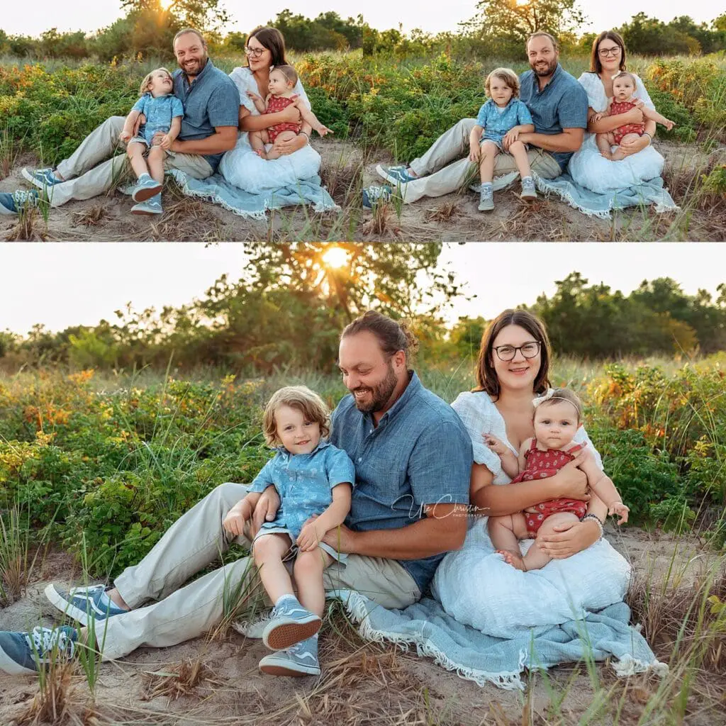 A family of four sits outdoors on a blanket among tall grass and wildflowers at sunset, smiling at the camera. The father and son sit together, while the mother holds the baby—perfect moments cherished by families and pediatricians in Milford CT.