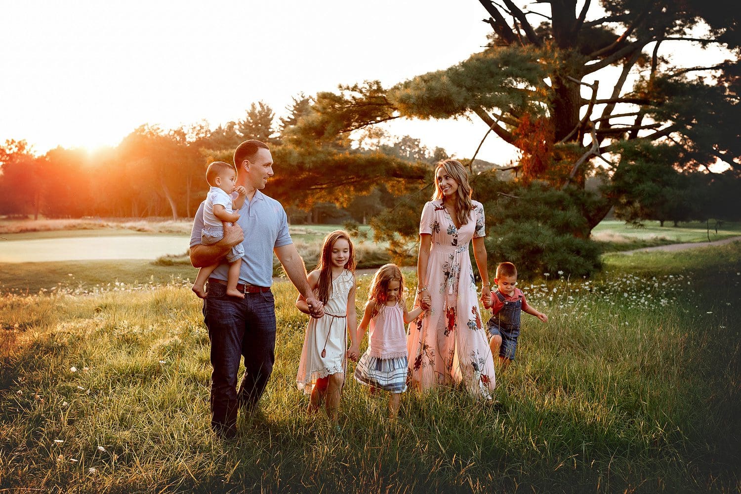 beautiful family of six walking through a field during sunset