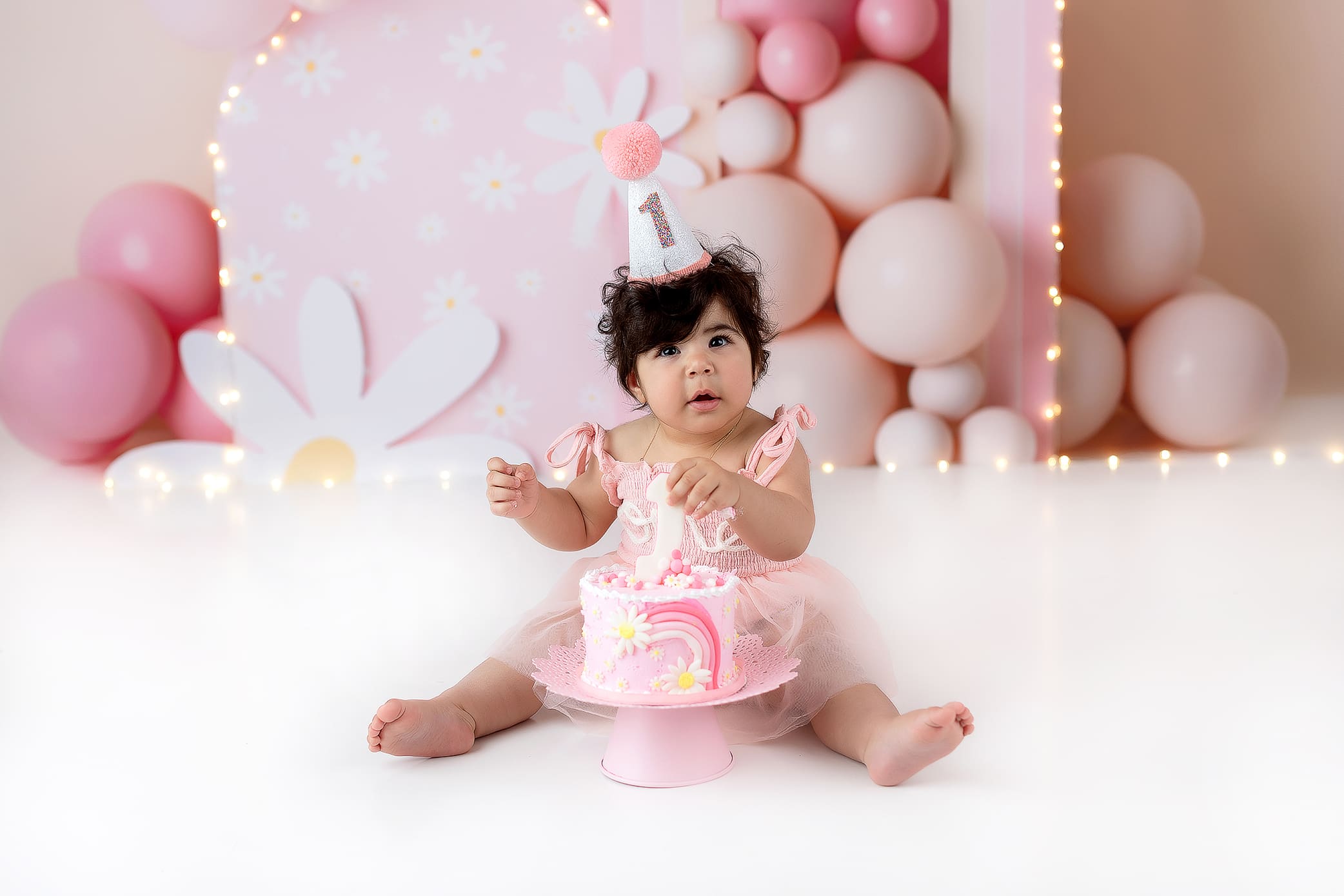 Adorable little girl with a pink outfit about to smah her cake