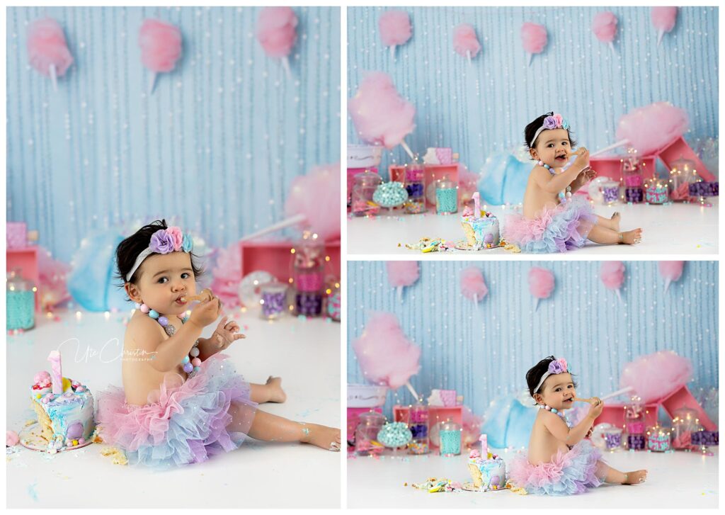A baby in a pastel tutu and floral headband sits on the floor surrounded by colorful sweets and decorations, enjoying a cake with cotton candy and treats in a whimsical, candy-themed setting.